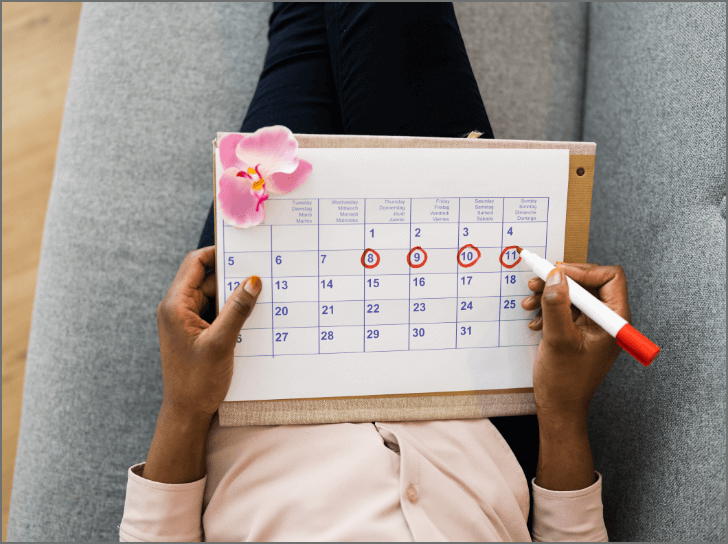 woman lying on couch marking dates on a calendar